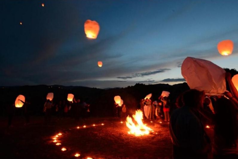 Lanterne luminose che salgono nel cielo al tramonto sulle colline